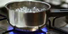 Water boils in a pot, runs out onto the stove sound 